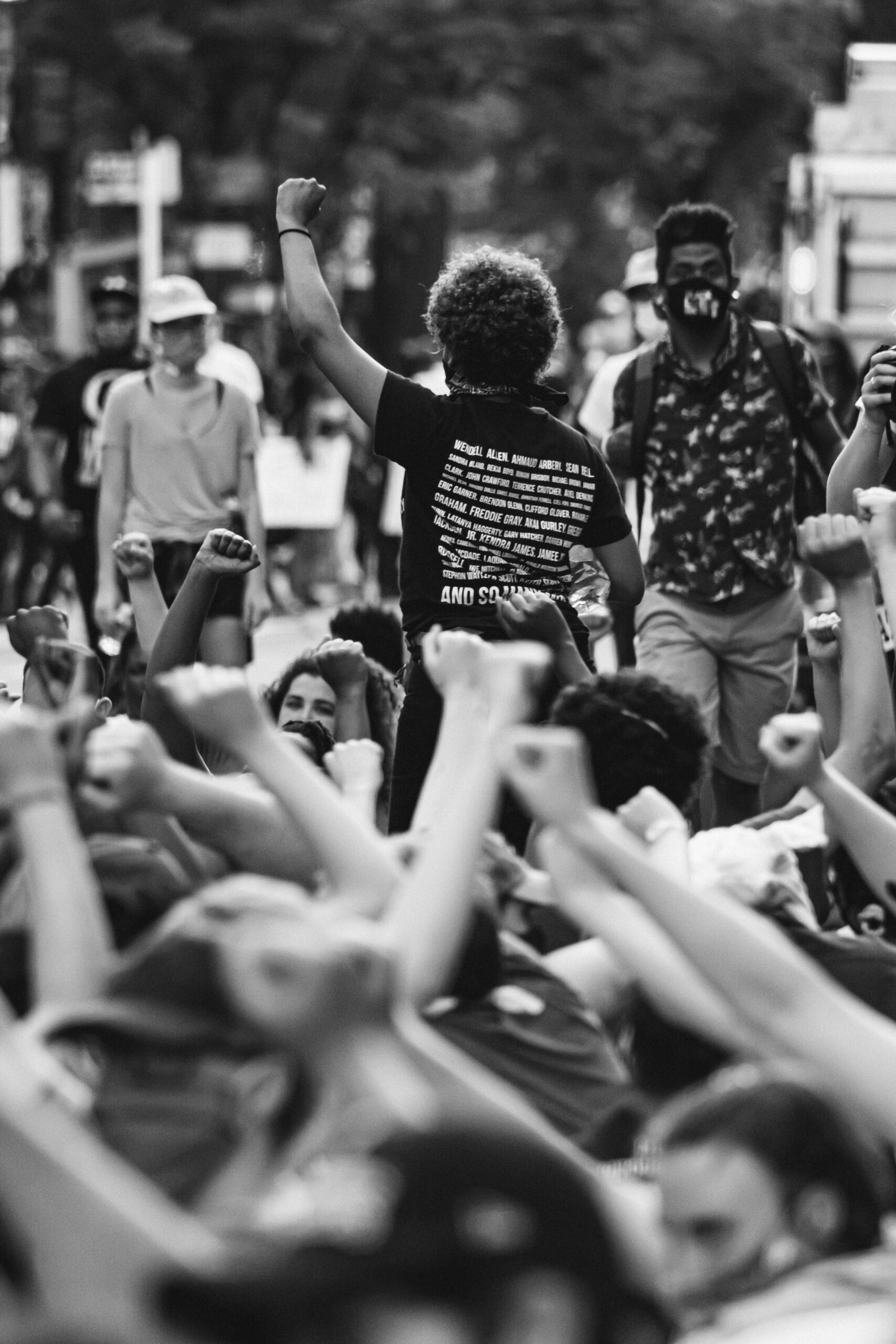 A crowd of protestors with fists clenched and raised in solidarity