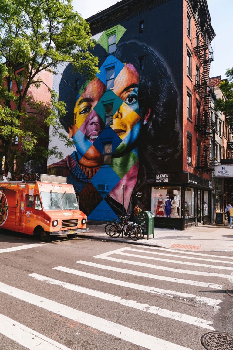 Street scene: a mural portrait of Michael Jackson - the left side of his face an early, the right side a late, MJ - covers the wall of a corner building.