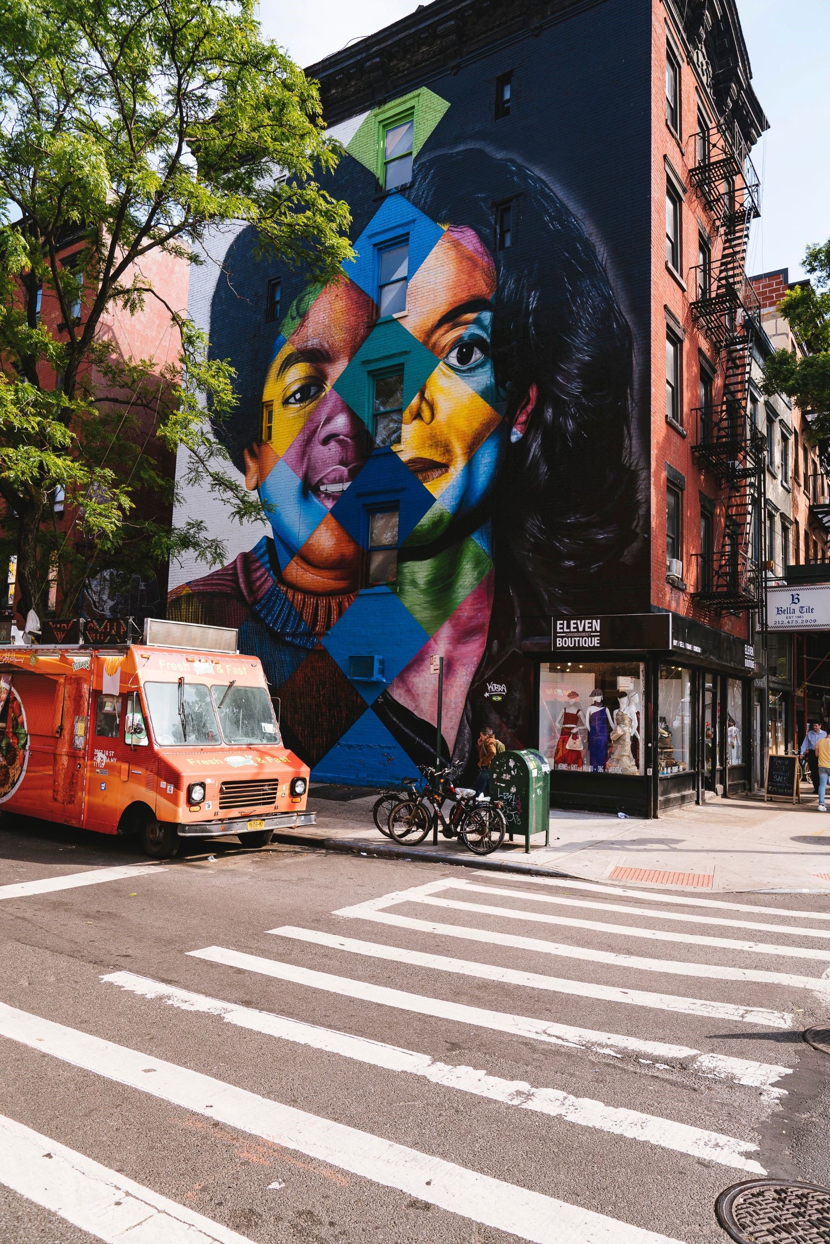 Street scene: a mural portrait of Michael Jackson - the left side of his face an early, the right side a late, MJ - covers the wall of a corner building.